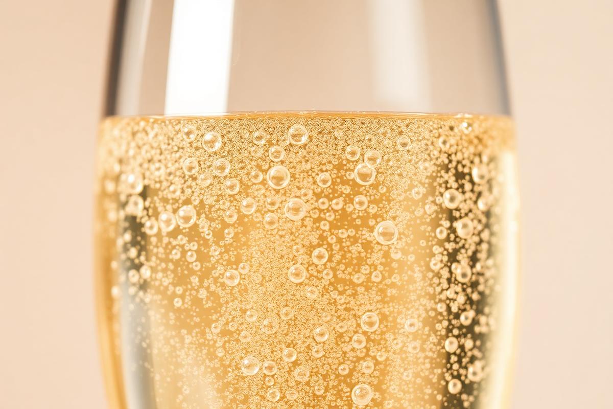 Macro photograph of golden bubbles rising in a champagne flute.